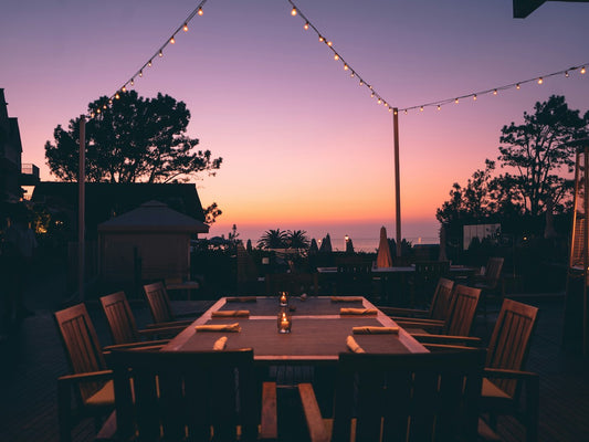 Outdoor dining table set with the sunset in the background.