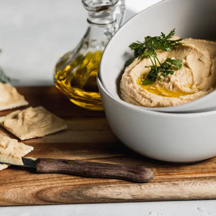 Crackers with hummus on a board.