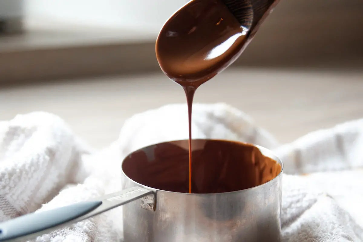 Dripping fudge sauce into a pan from a spoon.