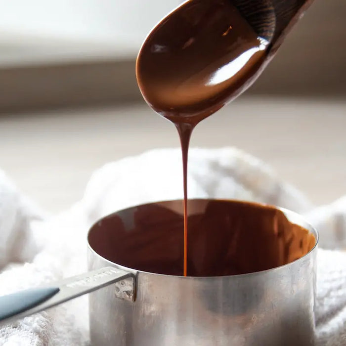 Dripping fudge sauce into a pan from a spoon.