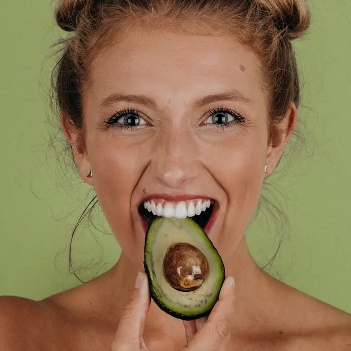 A girl eating an avocado.