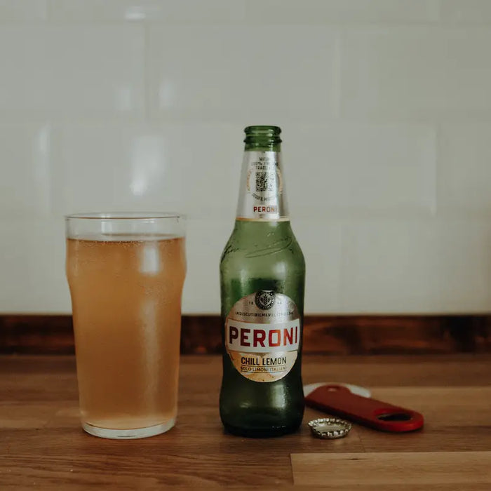 Bottle of peroni and a glass full of beer.