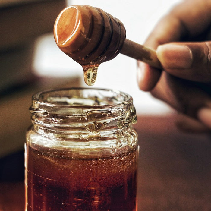 Honey poured into a glass jar.