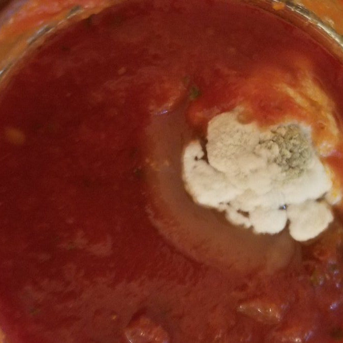 Tomato sauce with mold on it.