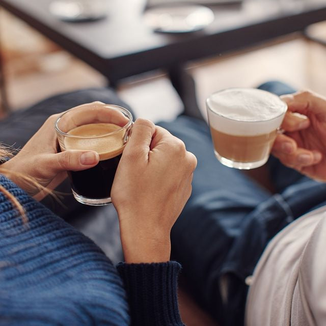 A couple holding cups of Nespresso coffee