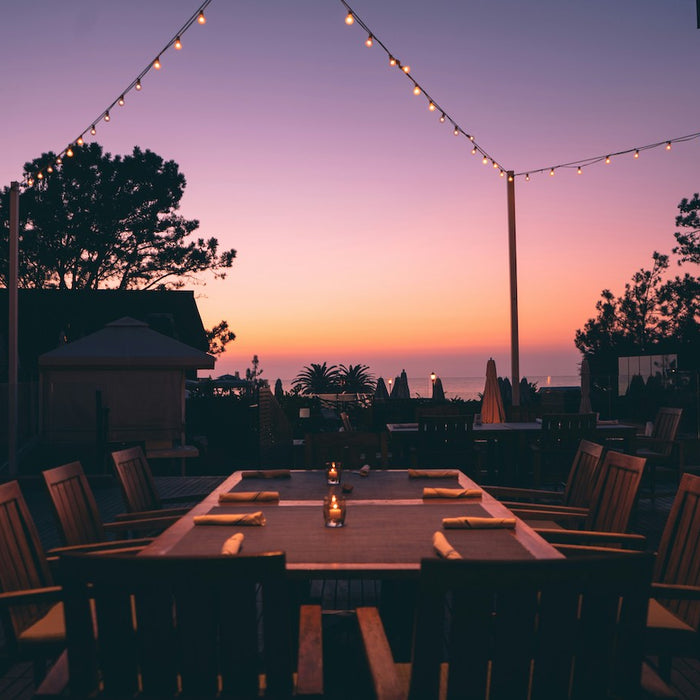 Outdoor dining table set with the sunset in the background.