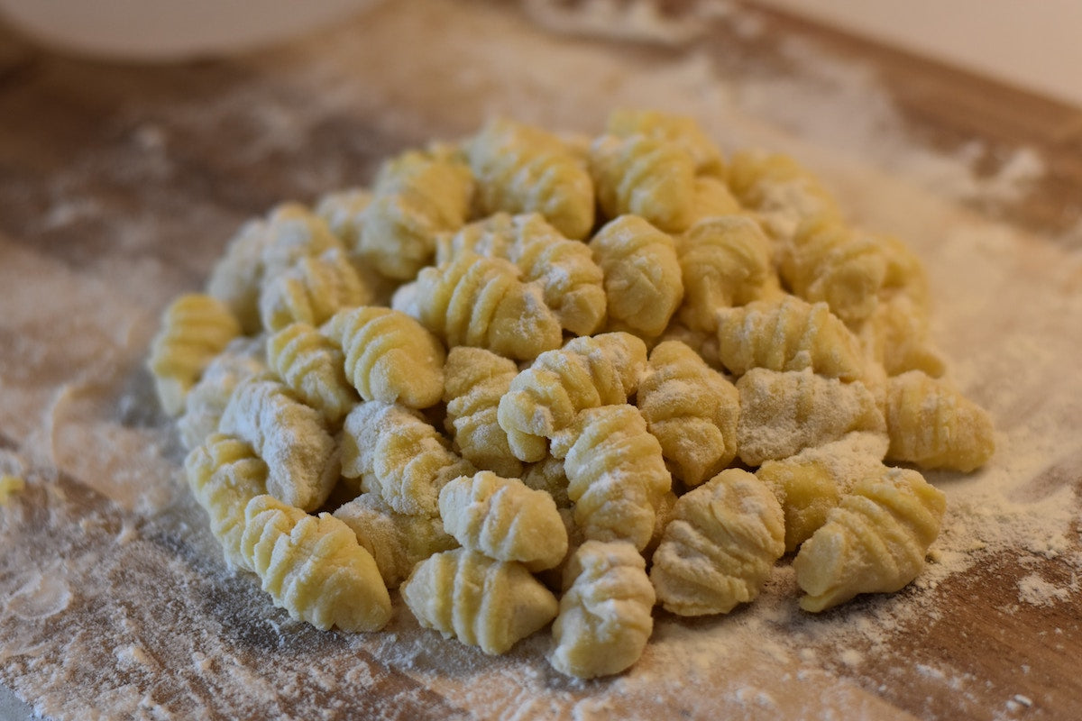 Uncooked gnocchi dough on a gnocchi board.