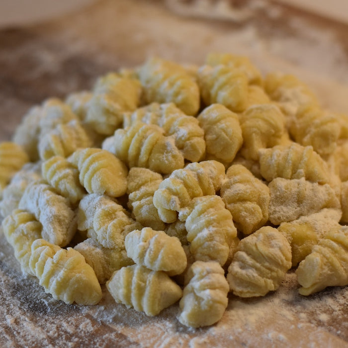 Uncooked gnocchi dough on a gnocchi board.