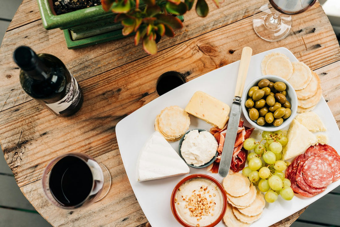 Wine, fruit, cheese and olives on a cheese board.